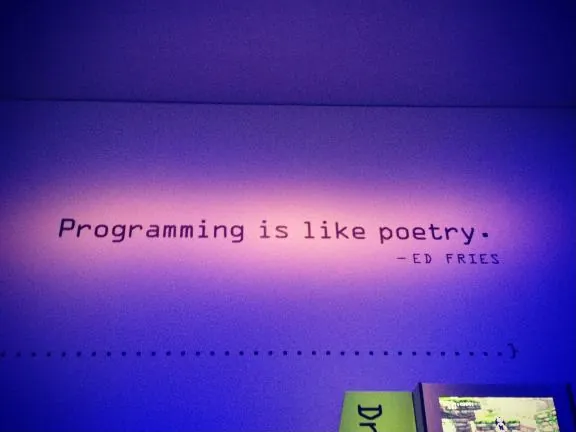 Wall text reading "Programming is like poetry." credited to Ed Fries