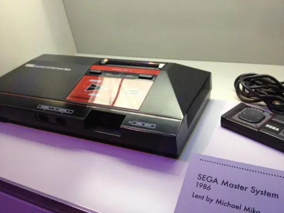 A Sega Master System console and controller in a museum case