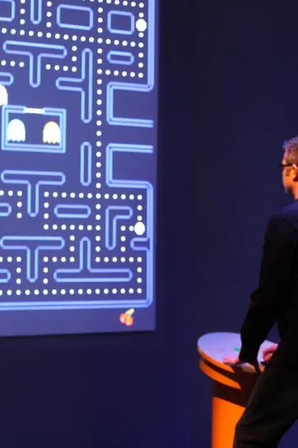 Chris Melissinos playing a wall-sized projection of Pac-Man at a game kiosk in the exhibition