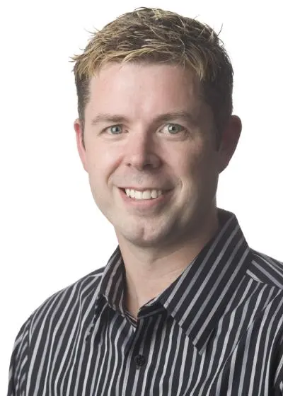 Studio headshot of Chris Melissinos in a striped shirt on a white background